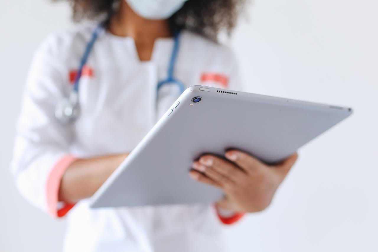 Close-up of a doctor wearing a mask using a tablet for healthcare management.